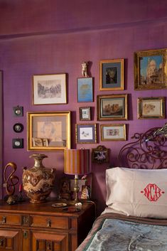 a bedroom with purple walls and pictures on the wall