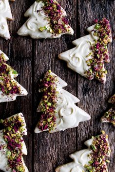 christmas tree shaped cookies with white frosting and sprinkles on a wooden table