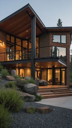 a modern house with wood and glass on the outside, surrounded by grass and rocks