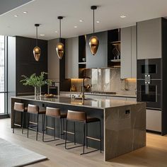 a kitchen with an island and bar stools in the center, along with several lights hanging from the ceiling