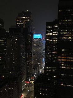 the city skyline is lit up at night, with skyscrapers in the foreground