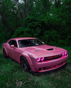 a pink sports car parked in the grass