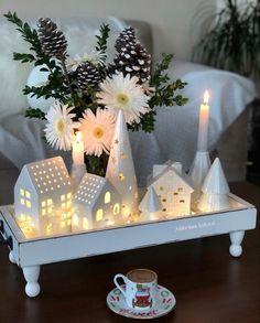 a tray with candles, flowers and houses on it