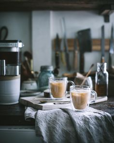 two cups of coffee sitting on top of a wooden table