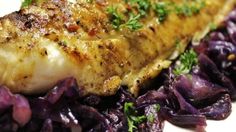 a piece of fish and purple cabbage on a white plate with garnishes