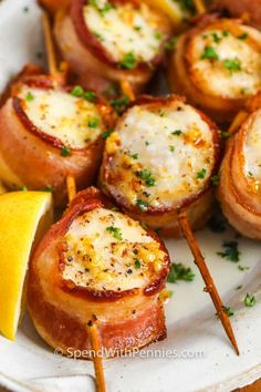 bacon wrapped lollipops on a plate with lemon wedges