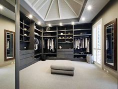 a large walk in closet with an ottoman