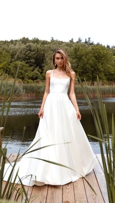 a woman in a white dress standing on a dock