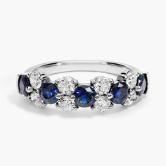 a blue and white diamond ring with three stones on the side, set in 18k white gold