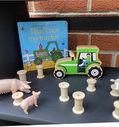 there is a toy tractor and farm animals on the table next to a children's book