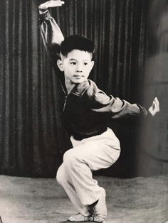 an old black and white photo of a young boy doing a dance move with his hands in the air