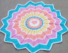 a colorful crocheted doily on the ground with a white circle in the center