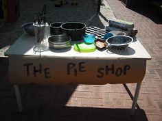 a table that has some pots and pans on it with the words the pie shop written on it