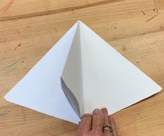 a person is holding an origami piece in their hand on a wooden table