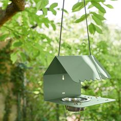 a green bird feeder hanging from a tree