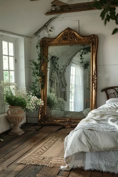 a bed sitting under a large mirror next to a plant filled window in a bedroom