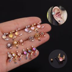 a hand holding several different types of ear piercings in various colors and designs on it