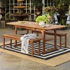 an outdoor dining table with benches and potted plants