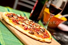 a pizza sitting on top of a wooden cutting board next to a glass of wine