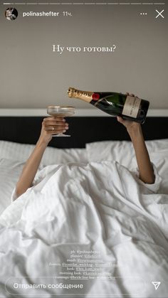 a woman laying in bed holding a bottle of champagne