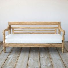 a wooden bench sitting on top of a hard wood floor next to a white wall