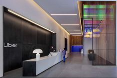 an office lobby with black walls and white counter tops, along with neon lights on the ceiling