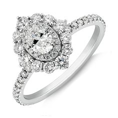 a white gold ring with an oval shaped diamond surrounded by small round brilliant cut diamonds