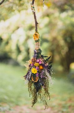 a flower arrangement hanging from a tree branch