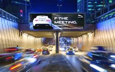 cars are driving under an overpass in the city at night, with billboards above them