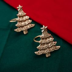 two christmas tree shaped rings sitting on top of a green cloth