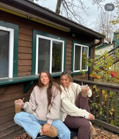 two women sitting on the porch drinking coffee and having fun with each other while holding beverages