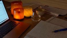 an open laptop computer sitting on top of a wooden desk next to a glass filled with water