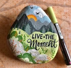 a rock with the words live the moment painted on it and a marker next to it