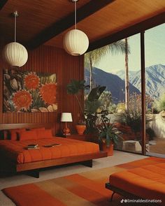 a living room with an orange couch and two white lamps hanging from it's ceiling