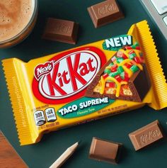 a kitkat chocolate bar sitting on top of a desk next to a cup of coffee