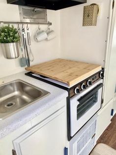 a small kitchen with an oven, sink and stove top in it's corner