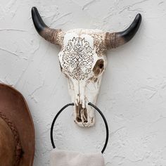 a cow skull mounted to the side of a white wall next to a hat rack