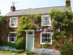 an old brick house covered in vines and flowers