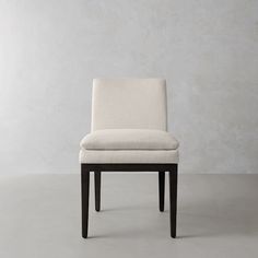 a white chair sitting on top of a gray floor next to a wall and a wooden frame