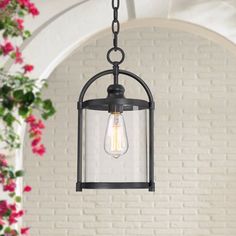 a light fixture hanging from a ceiling with pink flowers in the background and a brick wall behind it