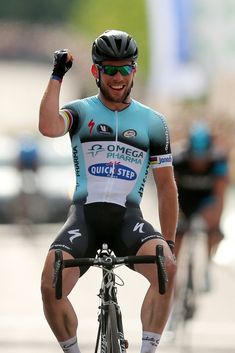 a man riding on the back of a bike while holding his fist in the air