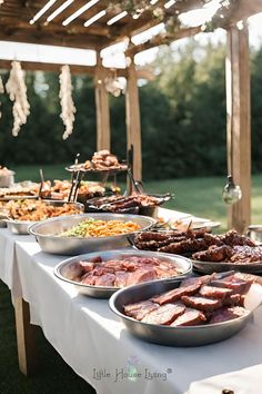 an outdoor buffet with meats and vegetables on it