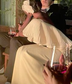 a man and woman sitting on a bench with wine glasses