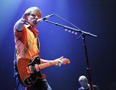 a man standing in front of a microphone while holding a guitar