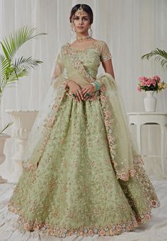 a woman in a green gown with flowers on the skirt and top, standing next to a