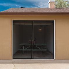 an open garage door with a picnic table in the center and blue sky behind it