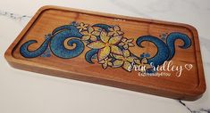 a wooden tray with blue and yellow designs on the front, sitting on a marble counter top