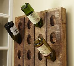 three bottles of wine are sitting on a wooden rack that is attached to the wall