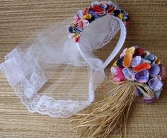 a white headband with flowers on it next to a piece of lace and a flower bouquet