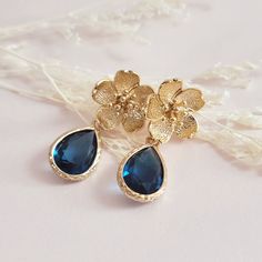 Navy Blue Flower Crystal Earrings for brides, weddings and bridal showers. The perfect gift earrings for bridesmaids, mother of the groom, or mother of the bride.  A gentle cascade of gold flowers and shimmering Blue crystals in these beautiful floral-inspired earrings. Adding just a hint of sparkle, this pretty pair make gorgeous earrings for both brides and bridesmaids. Simply stunning!  These beautiful floral earrings will complement any bridal style and make the perfect gift for bridesmaids Elegant Blue Earrings For Gift, Blue Gold Bridal Earrings, Elegant Blue Flower Earrings, Elegant Blue Flower Drop Earrings, Whimsical Blue Flower Earrings For Gift, Wedding Navy Blue, Blue Earrings Wedding, Gold Bridesmaid Jewelry, Blue Flower Earrings